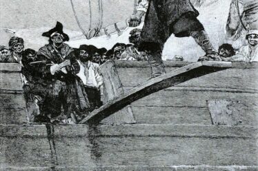 un uomo legato e bendato cammina su una passerella che sporge da una nave a vela. Alle sue spalle un pirata.