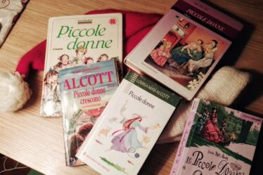 Varie edizioni dei libri di di Louisa May Alcott Piccole donne e Piccole Donne Crescono, adagiati sun cappello rosso e bianco di Babbo Natale