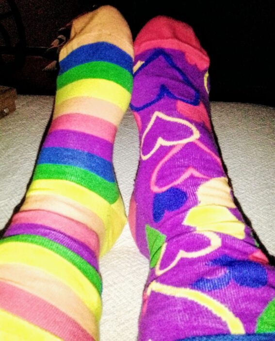 Due calzini spaiati uno a forma di arcobaleno uno a cuori, con colori abbinati.